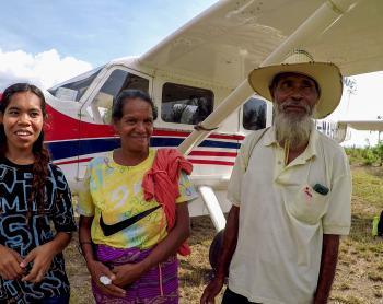 Three people stand by a small plane
