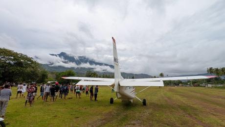 An MAF aircraft arrives at a remote airstrip of Maliana in Timor Leste where people gather to meet the flight