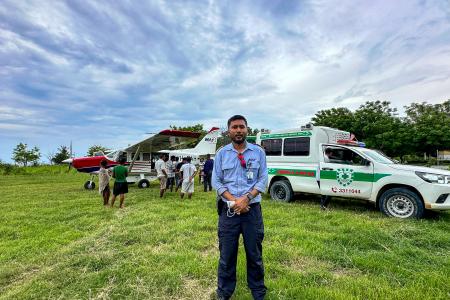 A pilot in front of a small plane and ambulance