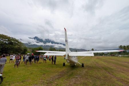 An MAF aircraft arrives at a remote airstrip of Maliana in Timor Leste where people gather to meet the flight