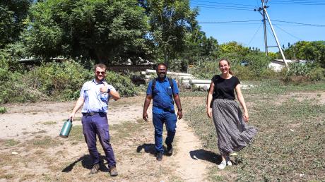 Three people walk towards the camera on an airstrip