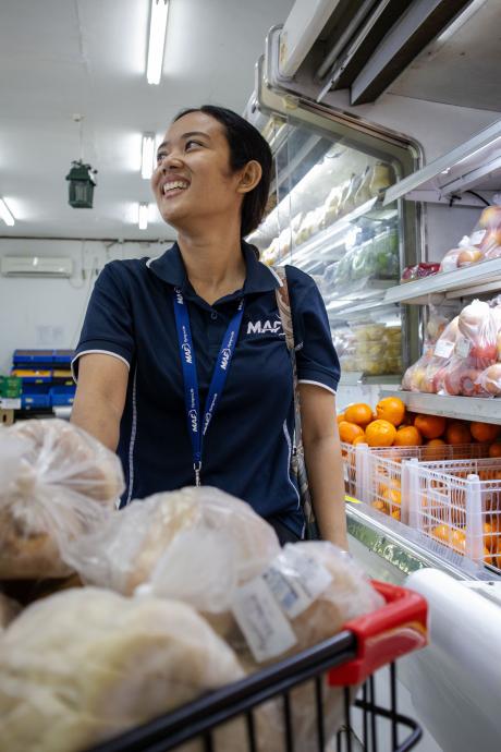A woman in a supermarket gathers goods from shelves