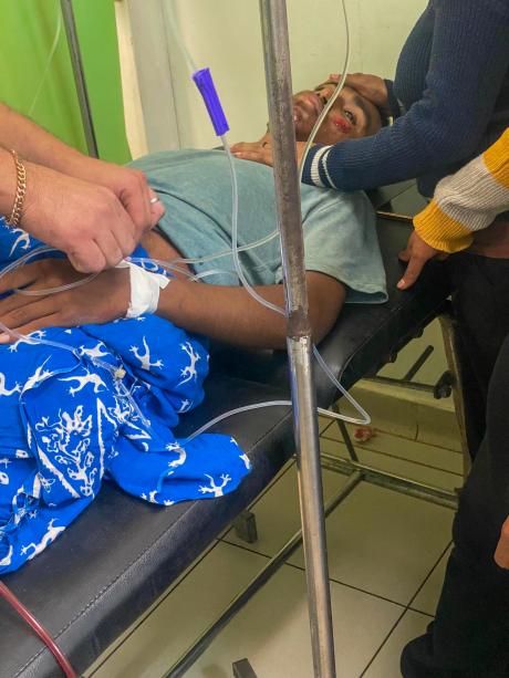 Cristiano receives treatment with an IV drip with family members nearby in a clinic in Maliana Timor Leste